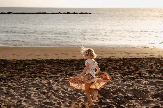 Little girl in flowing dress during beach play in lifestyle photography style