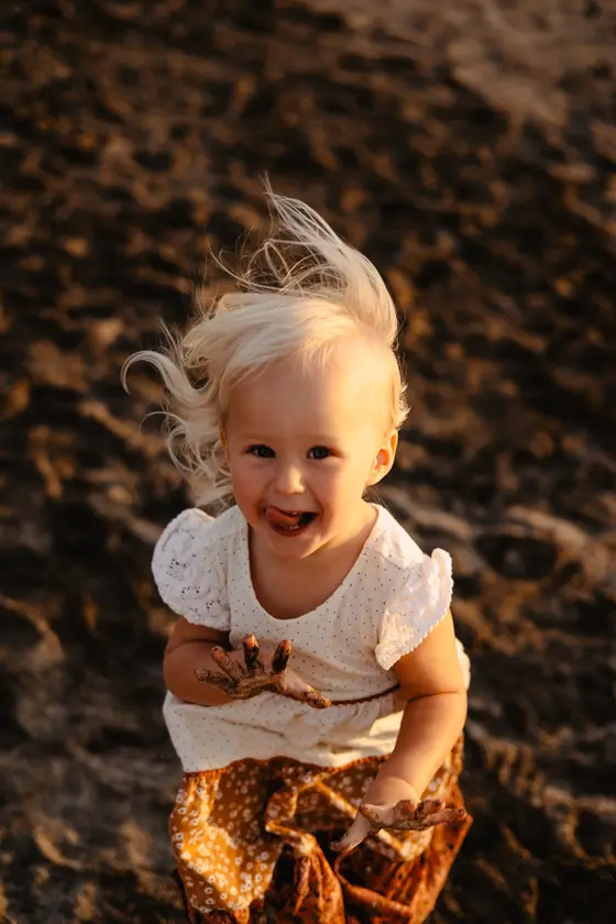 Happy little girl with flowing hair during spontaneous beach play lifestyle session