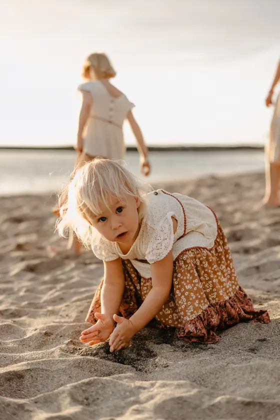 Small child playing in sand during family lifestyle photography session on beach