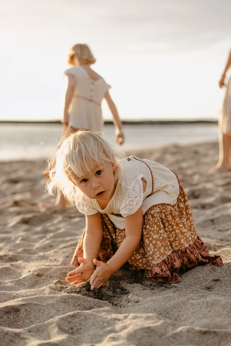 Small child playing in sand during family lifestyle photography session on beach