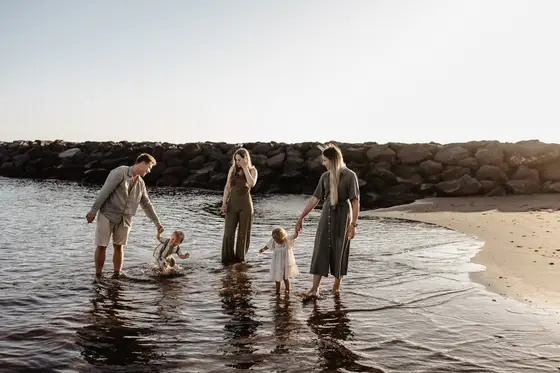 Familia caminando en agua en playa Tenerife durante sesión fotográfica hora dorada