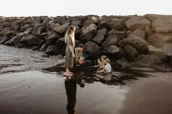 Familia jugando junto rocas volcánicas en playa Tenerife durante hora dorada fotografía
