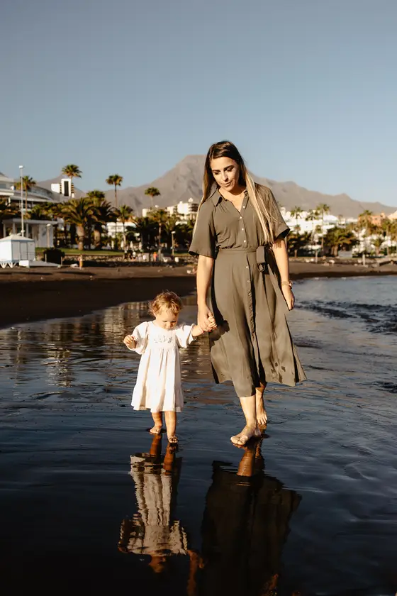 Madre e hija caminando en agua tomadas de mano durante sesión fotografía Tenerife