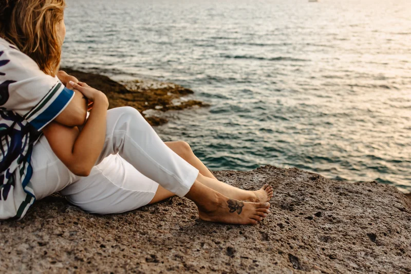 Momento íntimo pareja sentada junto orilla océano durante sesión fotografía familiar naturaleza Tenerife salvaje