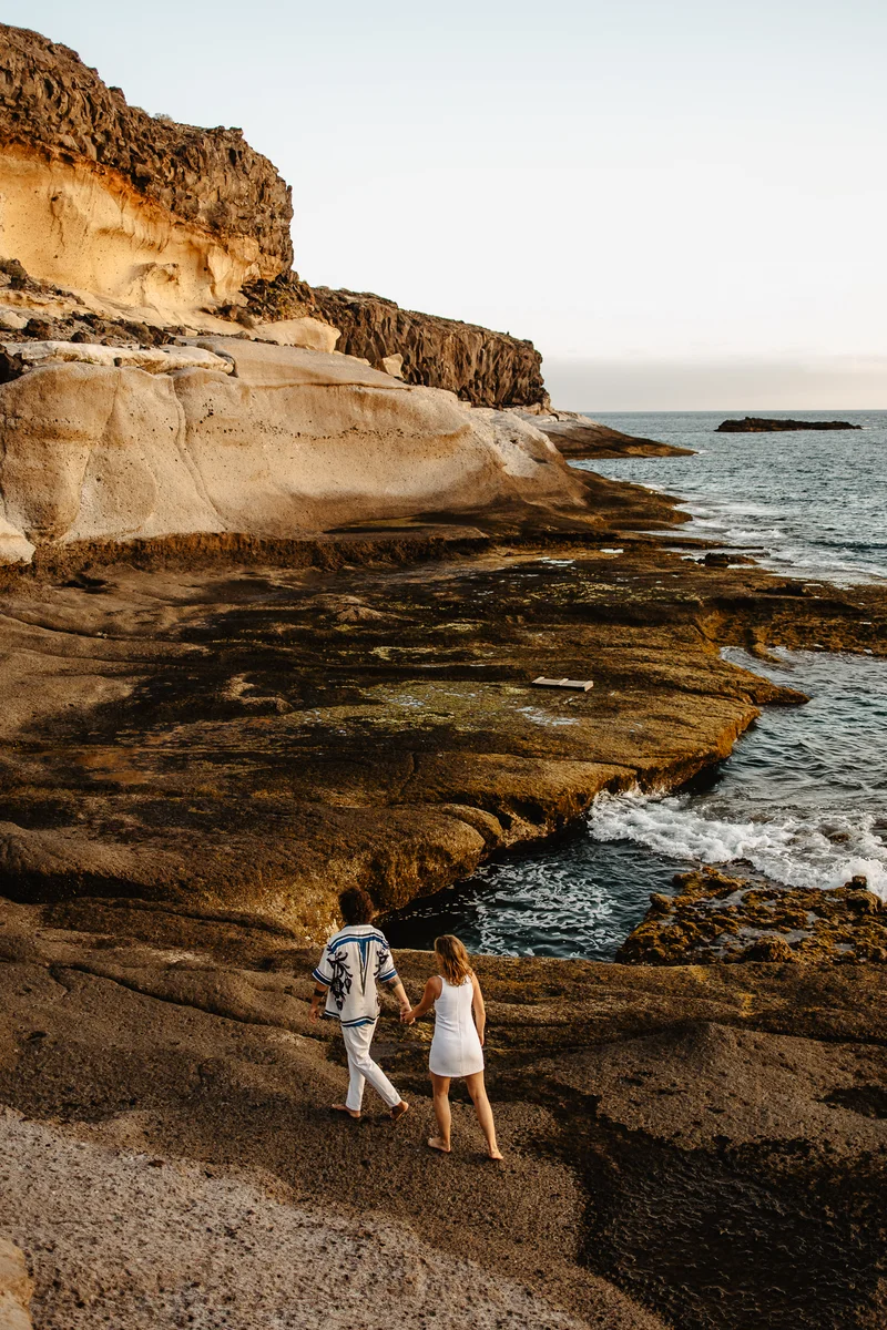 Pareja romántica caminando por rocas costeras durante sesión familiar en rincones salvajes naturaleza Tenerife