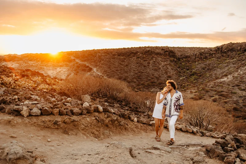 Pareja caminando junta por terreno salvaje Tenerife durante fotografía familiar naturaleza luz dorada atardecer