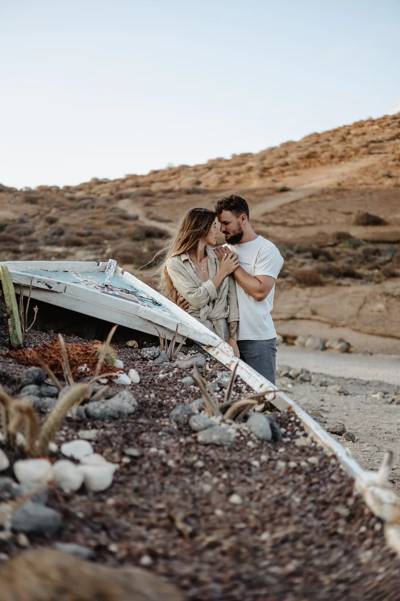 Beso romántico de pareja junto a barca vieja en Montaña Amarilla Tenerife sesión