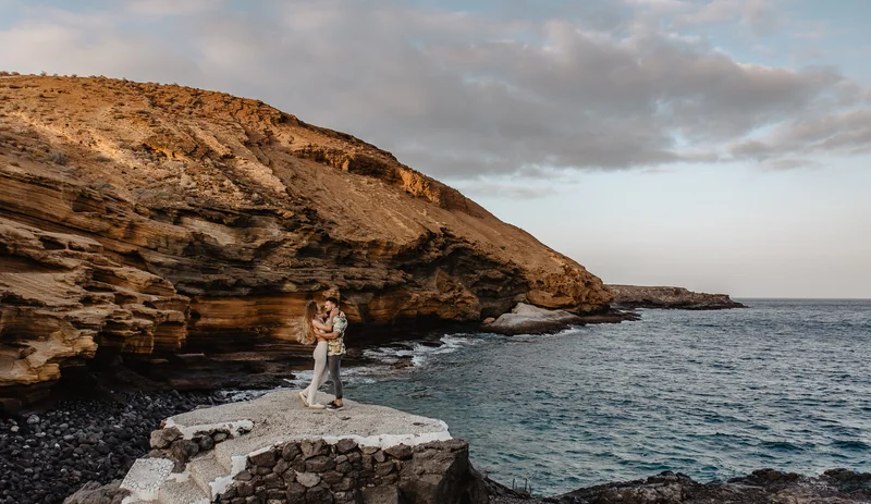 Pareja de pie en acantilado sobre océano Montaña Amarilla Tenerife sesión preboda
